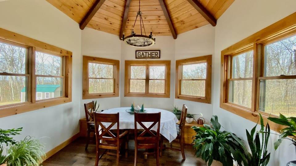 Photo of dining area in a rounded alcove of a log home with a turret style exposed wood ceiling