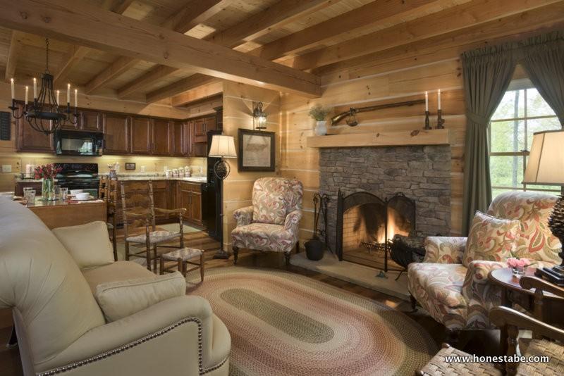 Photo of cozy family room with chink exposed wood walls. a traditional stone faced fireplace and wood mantle create a transition space to a dining/open kitchen with matching wood cabinets